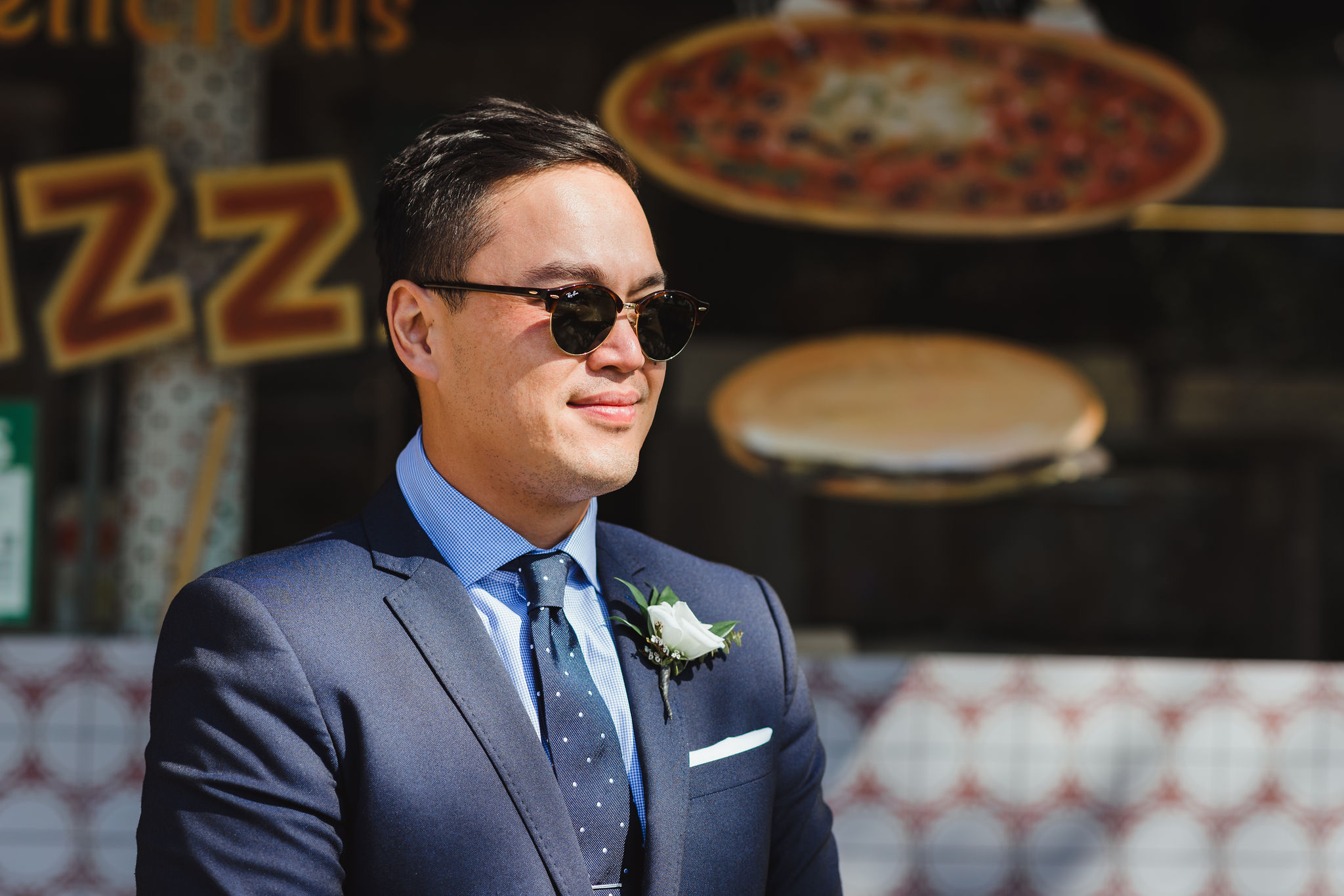 grooms in a blue suit and polkadot tie with white boutonniere standing in front of Bitondo's Pizzeria Toronto Canada 