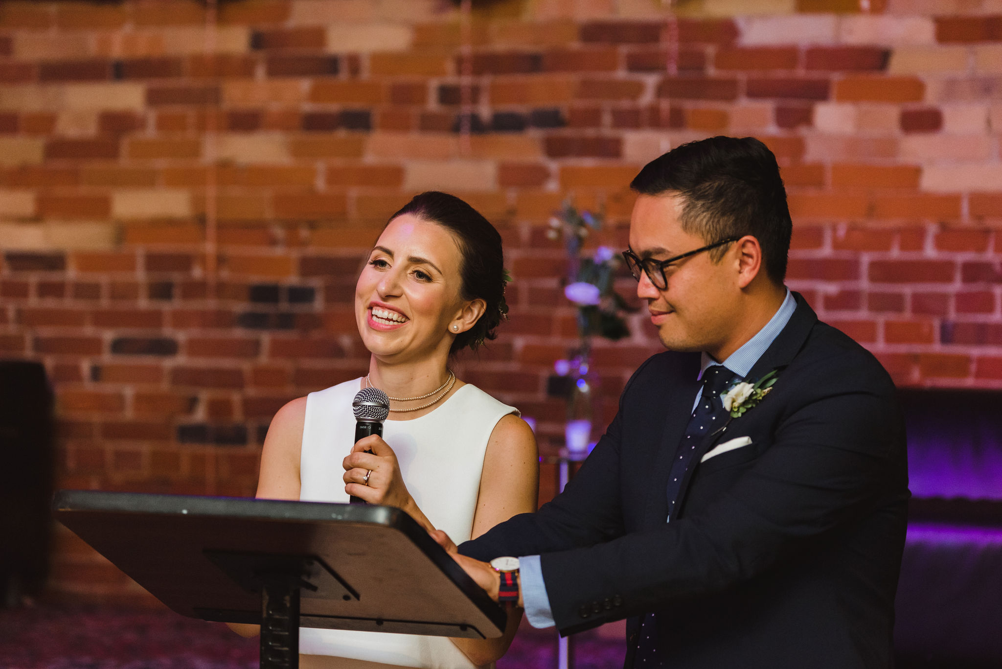 bride smiling as she and the groom give their speech from the podium at the Gladstone Hotel in Toronto