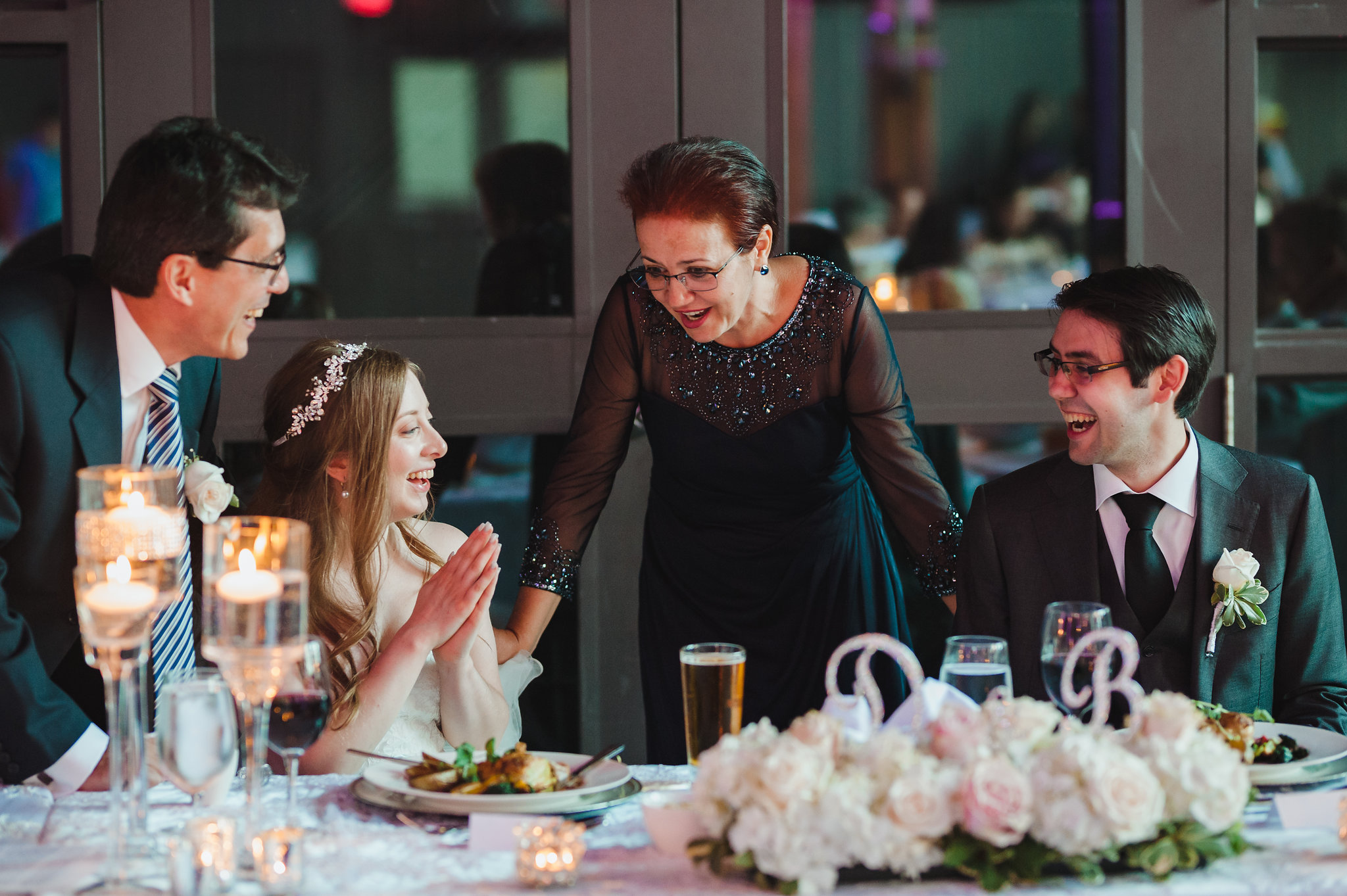 mother and father of the groom speaking to the bride and groom at the head table Steam Whistle Brewing wedding photography