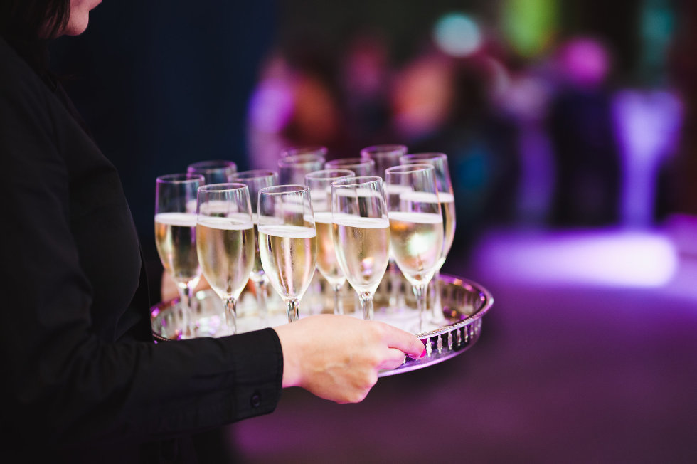 waiter carrying glasses of champagne through Steam Whistle