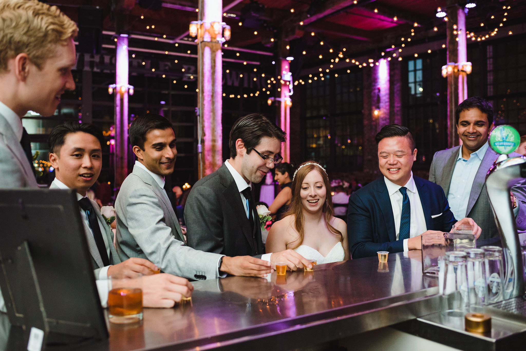 bride and groom about to take a shot with wedding guests at the bar inside Steam Whistle Brewing Toronto wedding photography Gillian Foster