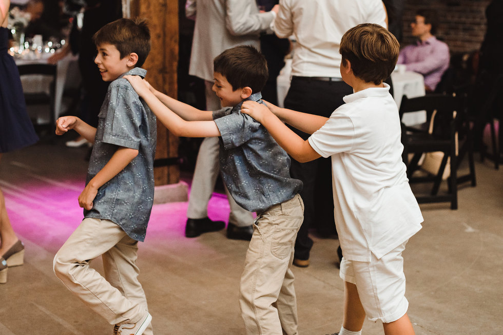 three little boys forming a conga line during a wedding at Steam Whistle Brewing