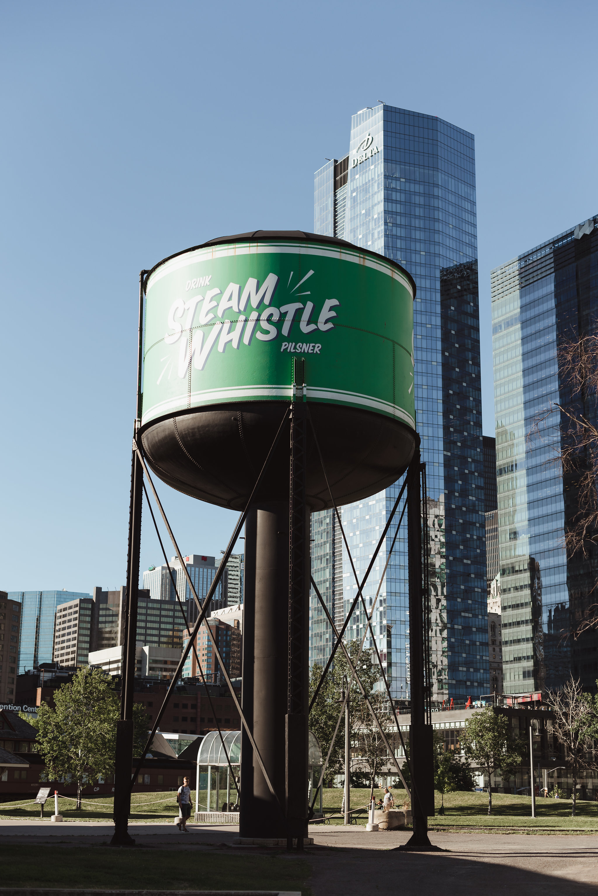 green and white Steam Whistle Brewing water tower in front of Toronto skyline