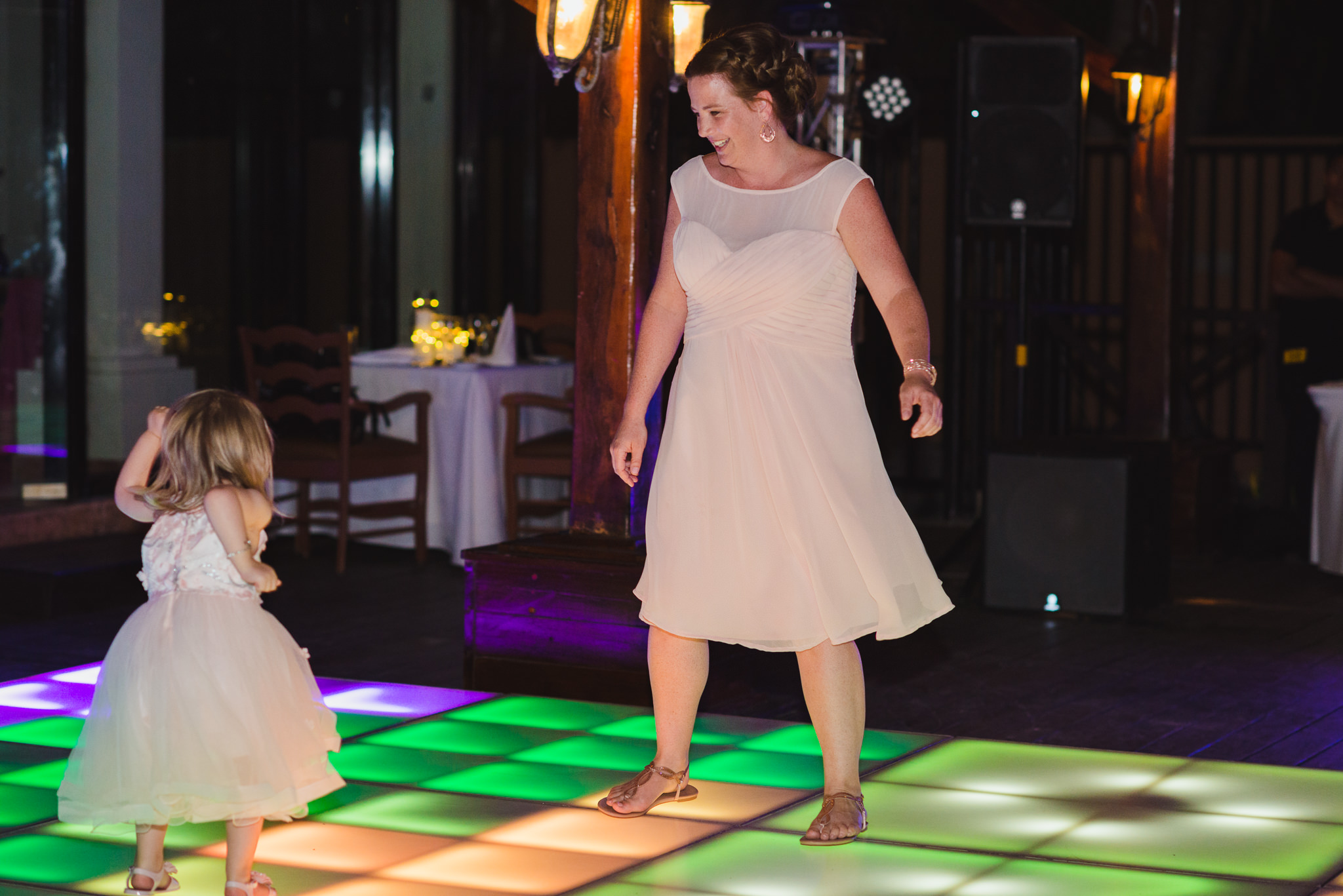 wedding guest and her little girl dancing on multi-coloured light up dance floor during wedding reception at Now Sapphire Resort in Mexico
