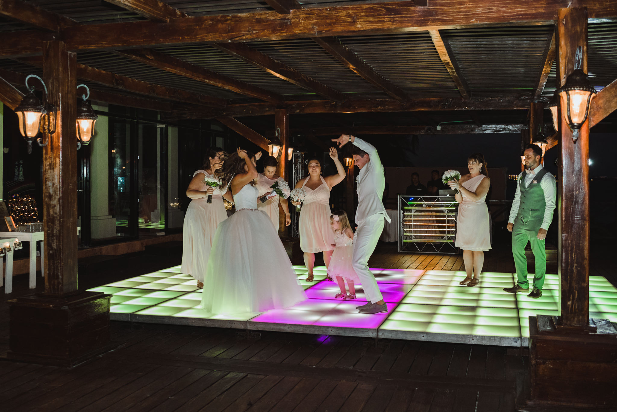 brides and wedding guests dancing on multi-coloured light up dance floor during wedding reception at Now Sapphire Resort in Mexico