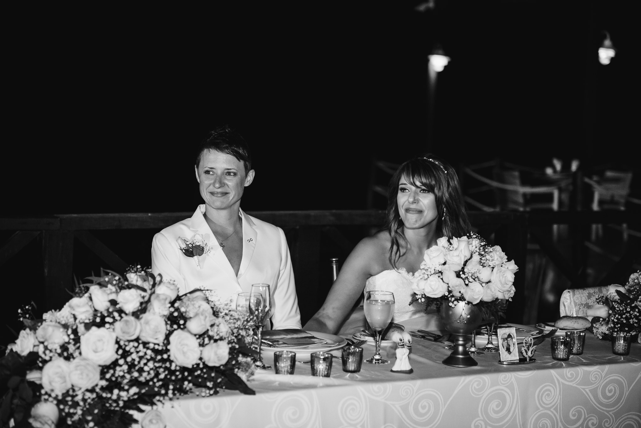 brides smiling and teary while sitting at head table and listening to speeches during wedding reception at Now Sapphire Resort in Mexico