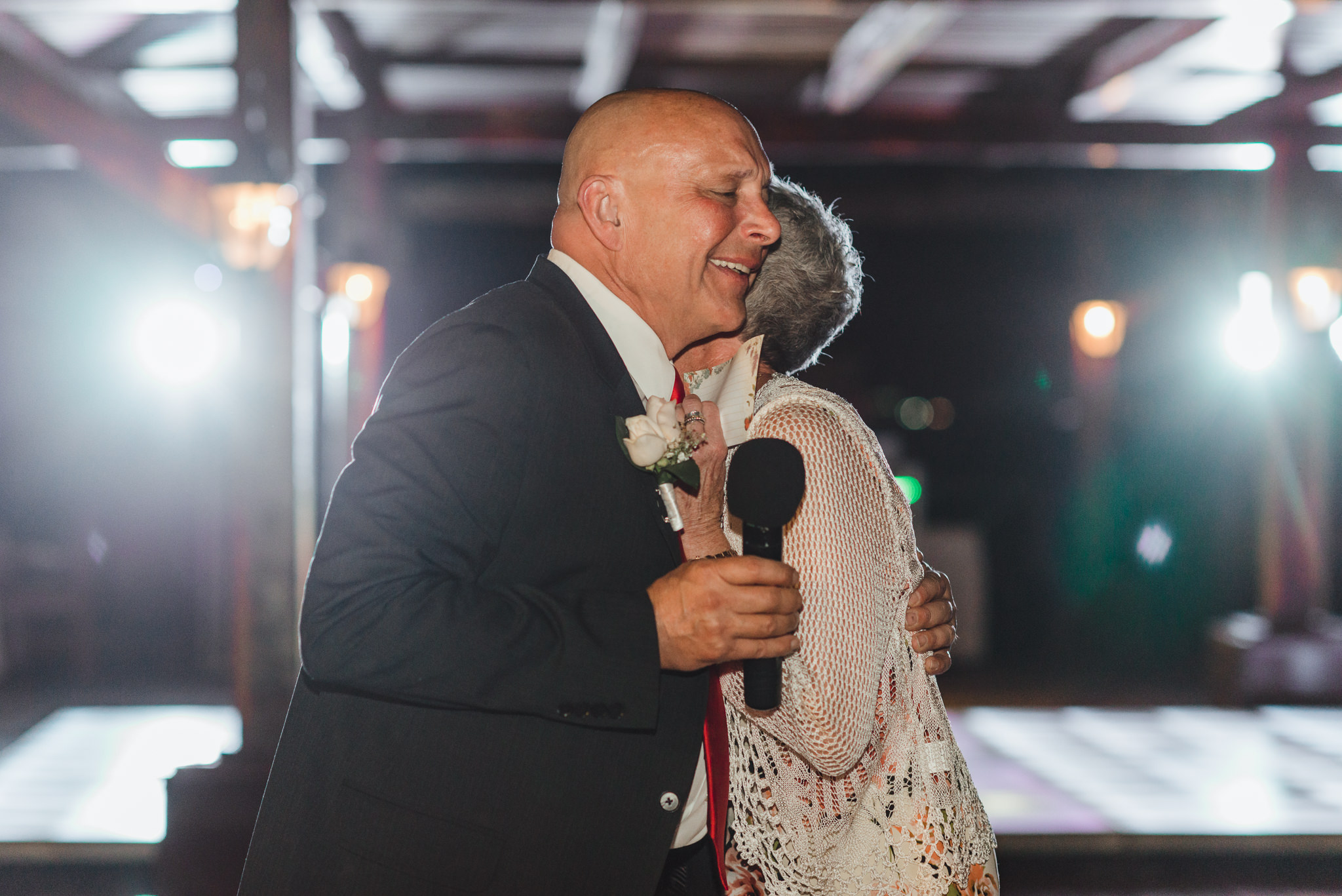 parents of the bride hug while giving wedding speech at Now Sapphire Resort in Mexico