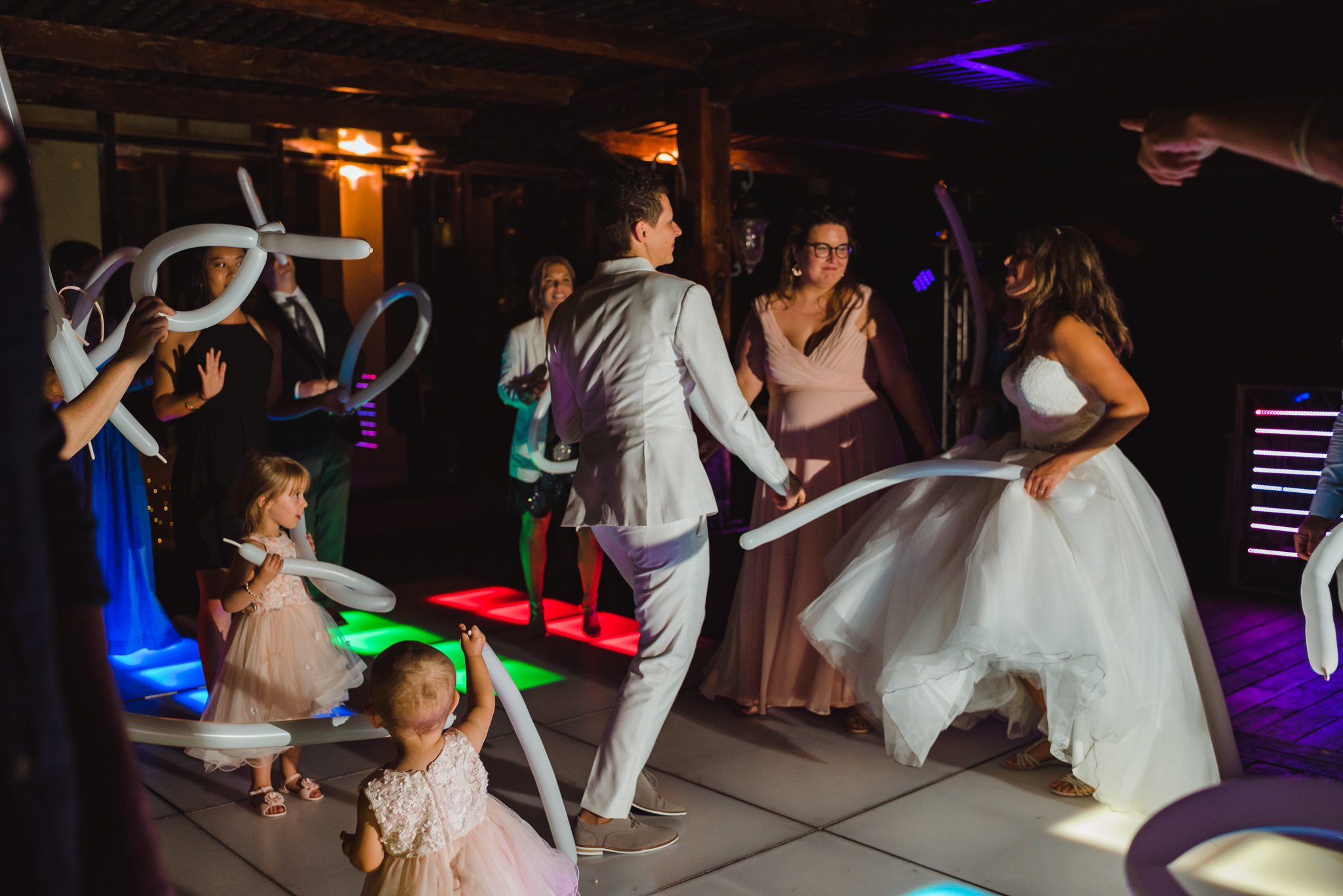 brides and their wedding guests partying with ballon animals on multi-coloured light up dance floor wedding reception at Now Sapphire Resort in Mexico