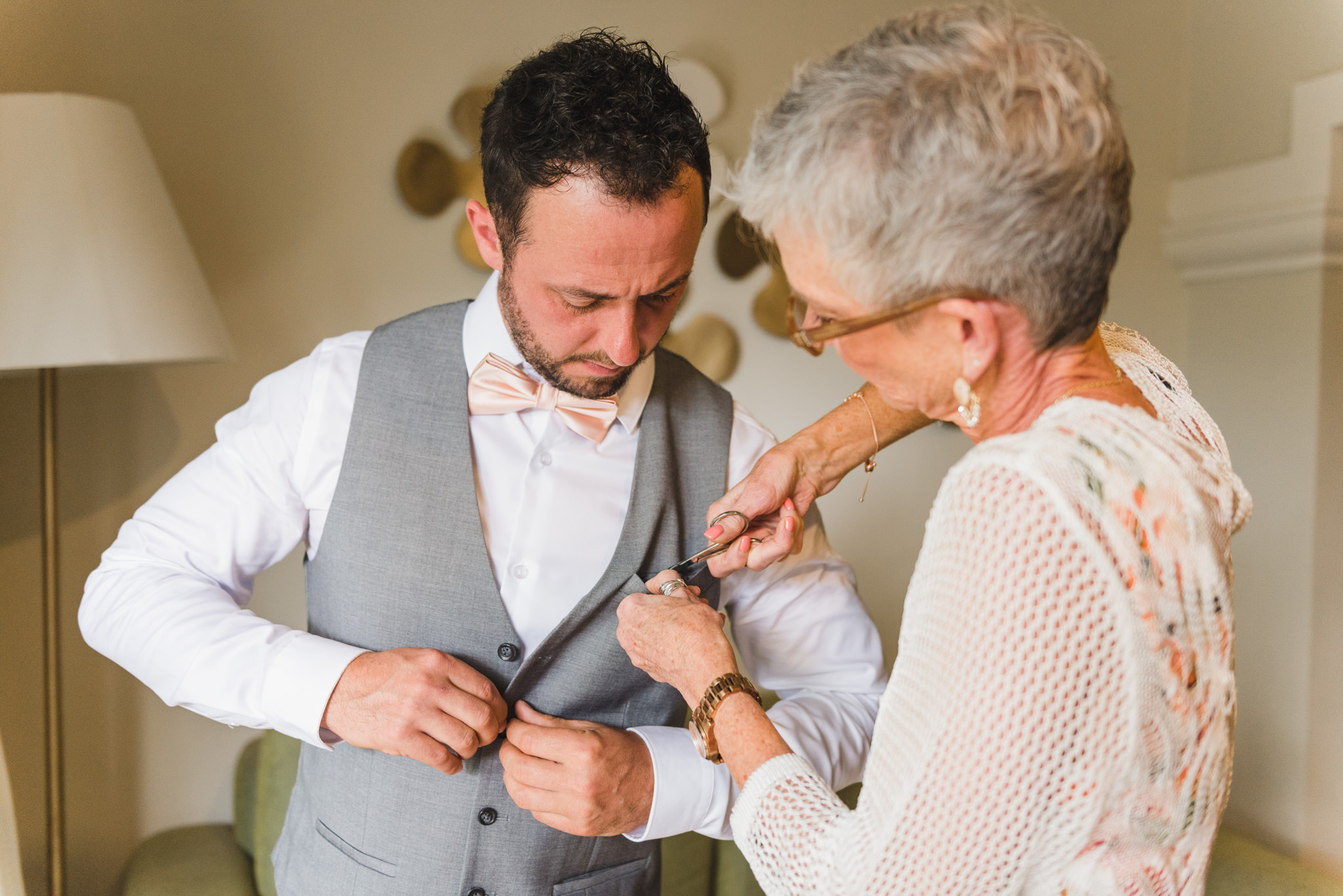 woman with scissors making alterations to a mans vest before wedding at Now Sapphire Resort in Mexico 