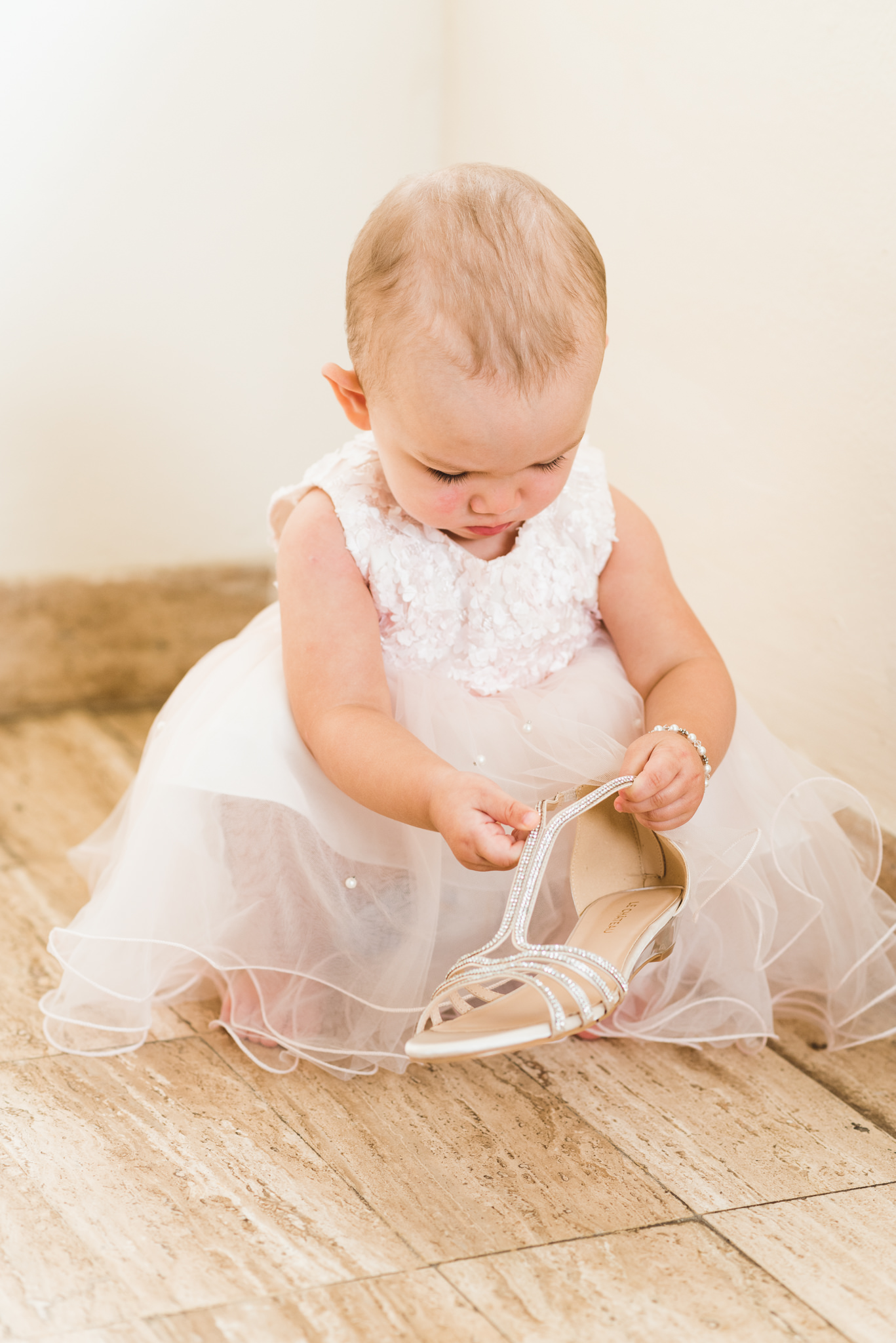 baby in a dress examining brides wedding shoe before ceremony at Now Sapphire Resort in Mexico