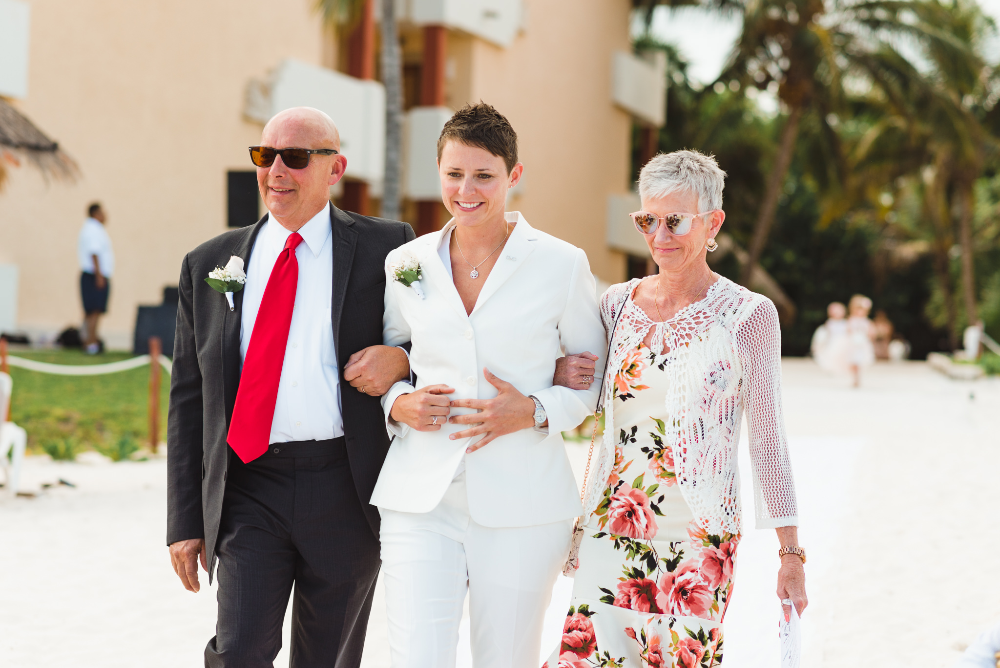 bride being walked down the aisle by her mother and father during beach ceremony at Now Sapphire Resort in Mexico