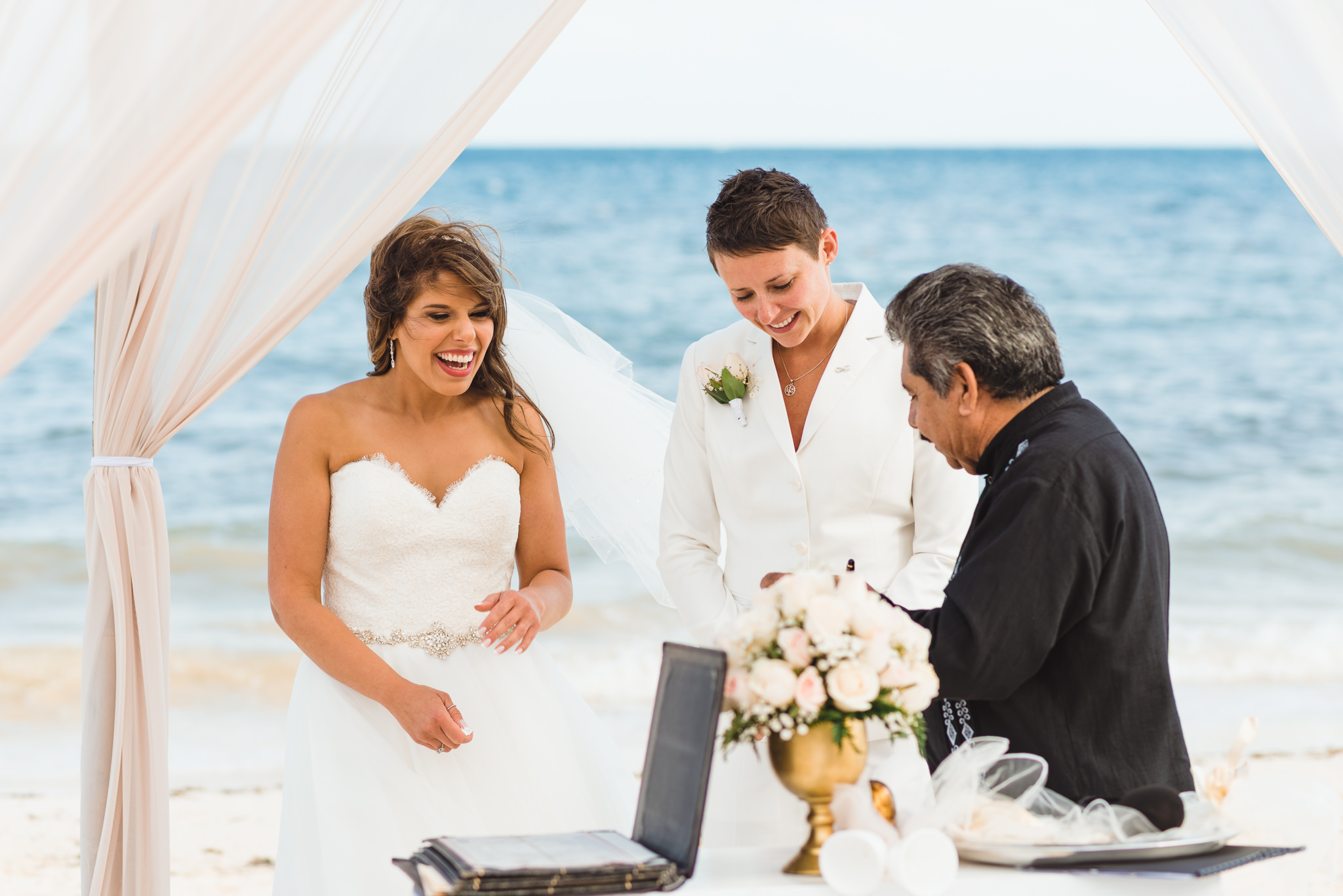 brides smiling at the alter as beach ceremony at Now Sapphire Resort in Mexico begins