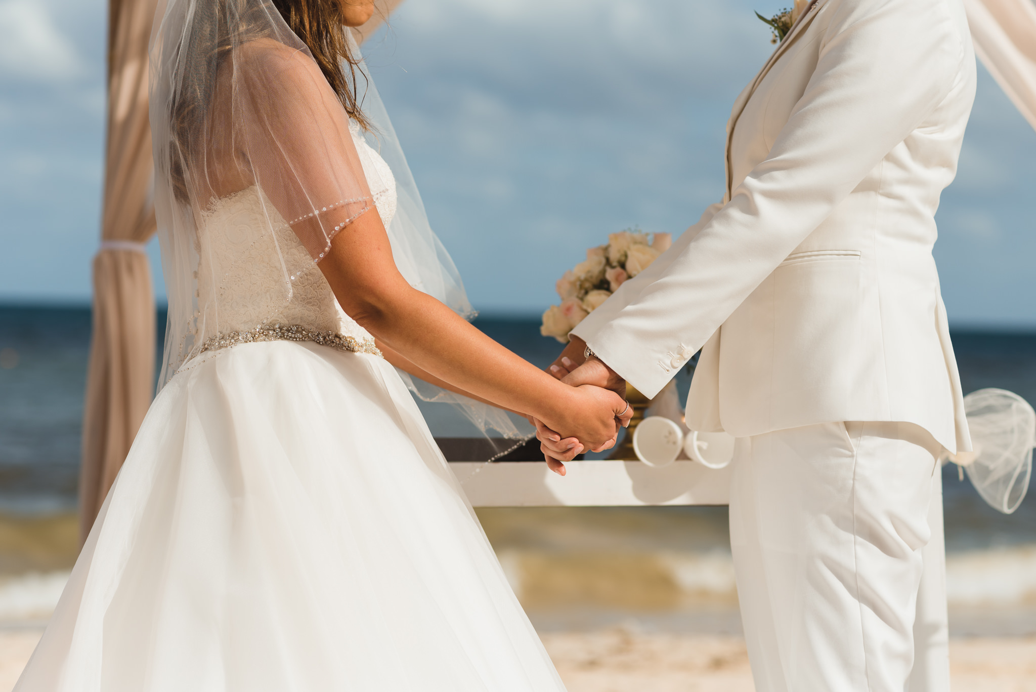 brides holding hands during beach ceremony at Now Sapphire Resort in Mexico