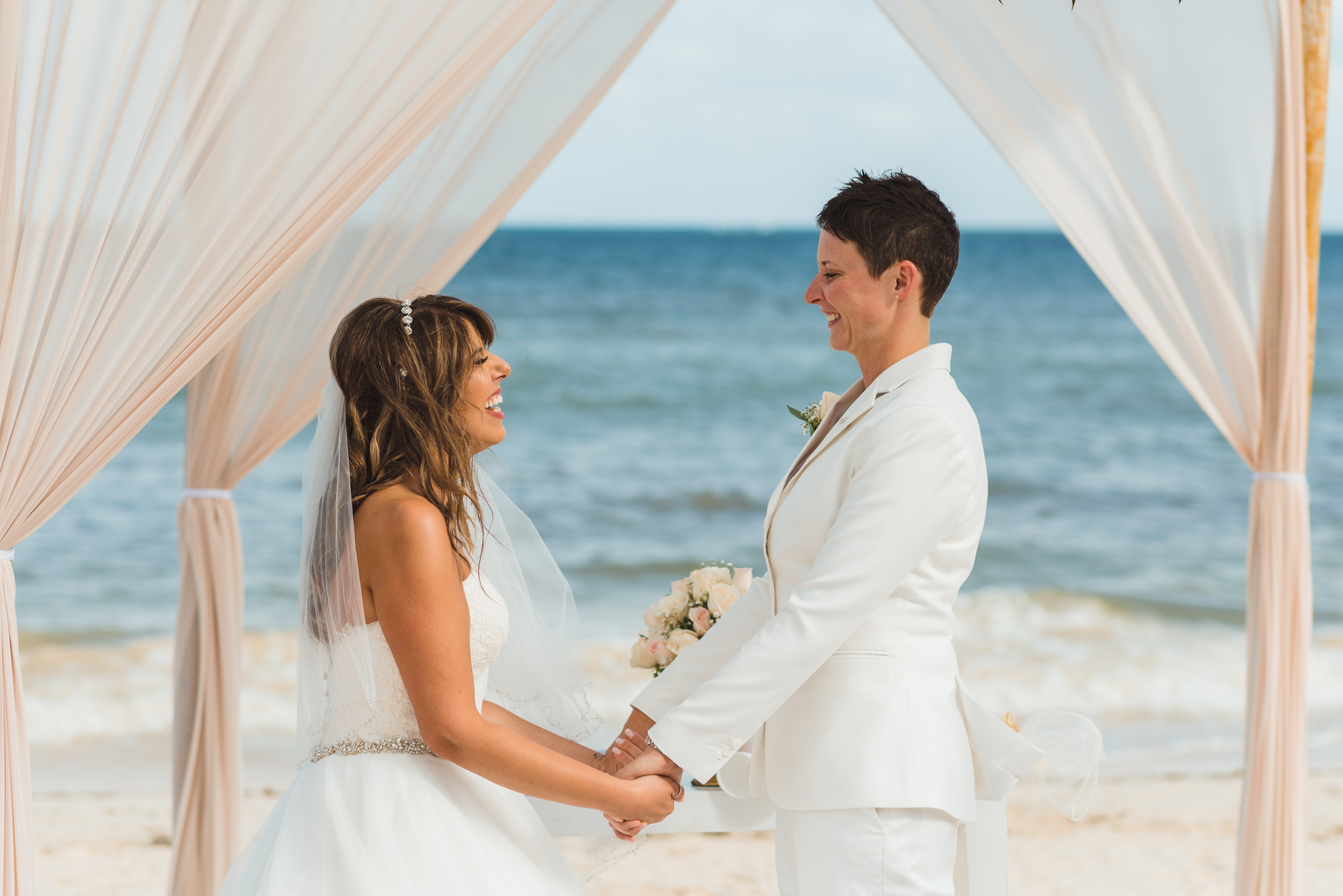 brides holding hands during beach ceremony in front of ocean at Now Sapphire Resort in Mexico