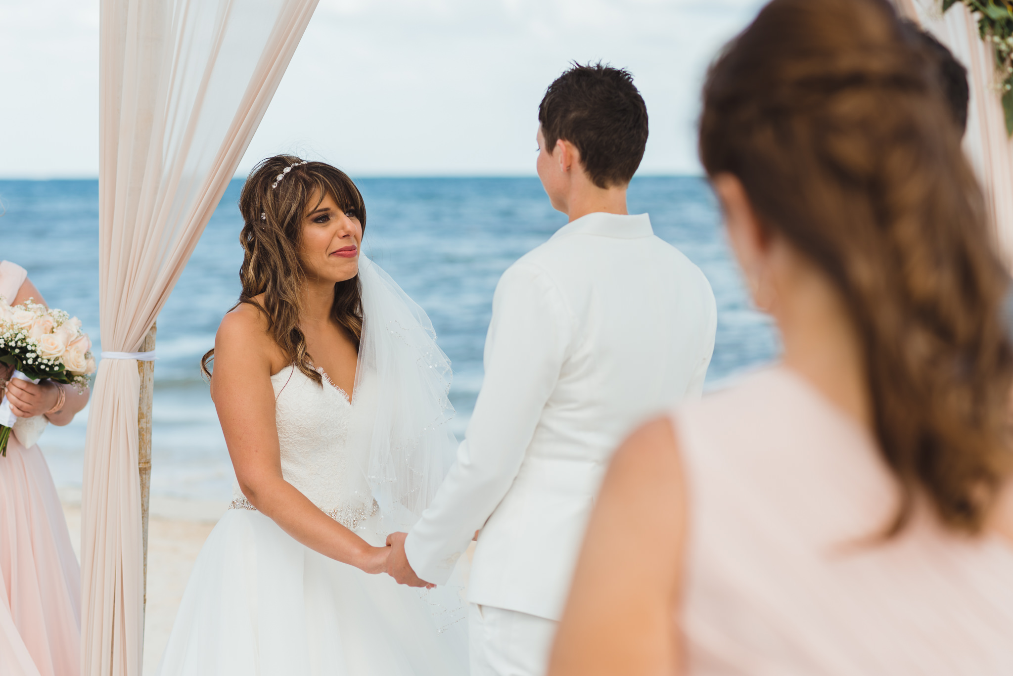 bride tearing up while holding hands during beach ceremony in front of ocean at Now Sapphire Resort in Mexico