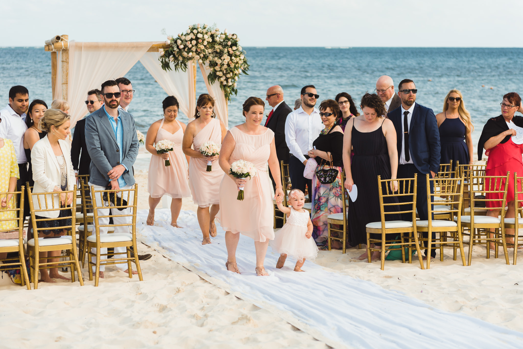 wedding party and guests exit beach ceremony in front of ocean at Now Sapphire Resort in Mexico