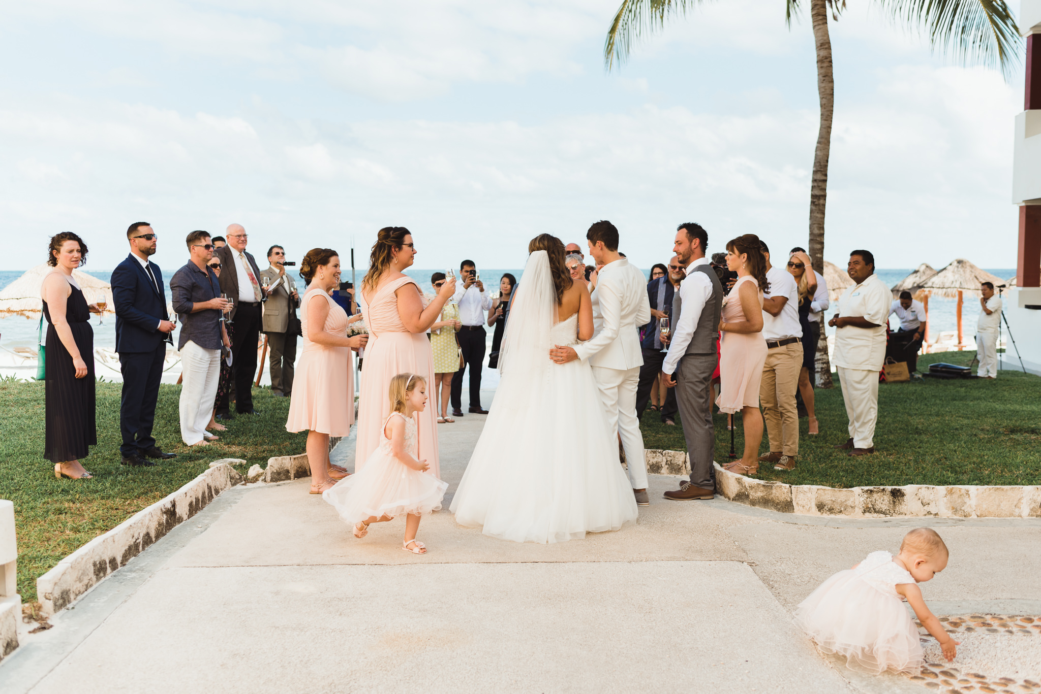 brides holding a toast with wedding guests after wedding ceremony in front of ocean at Now Sapphire Resort in Mexico