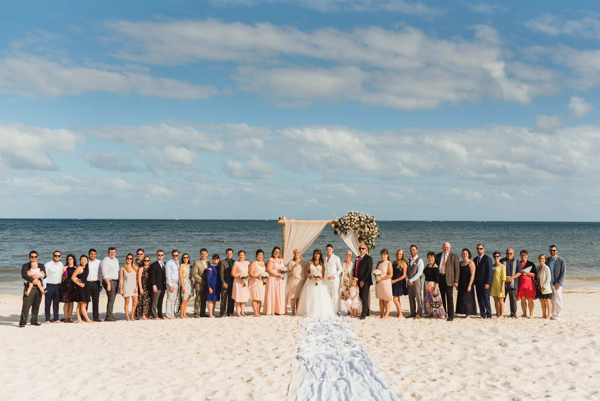 brides and their wedding guests lined up at alter in front of the ocean at Now Sapphire Resort in Mexico
