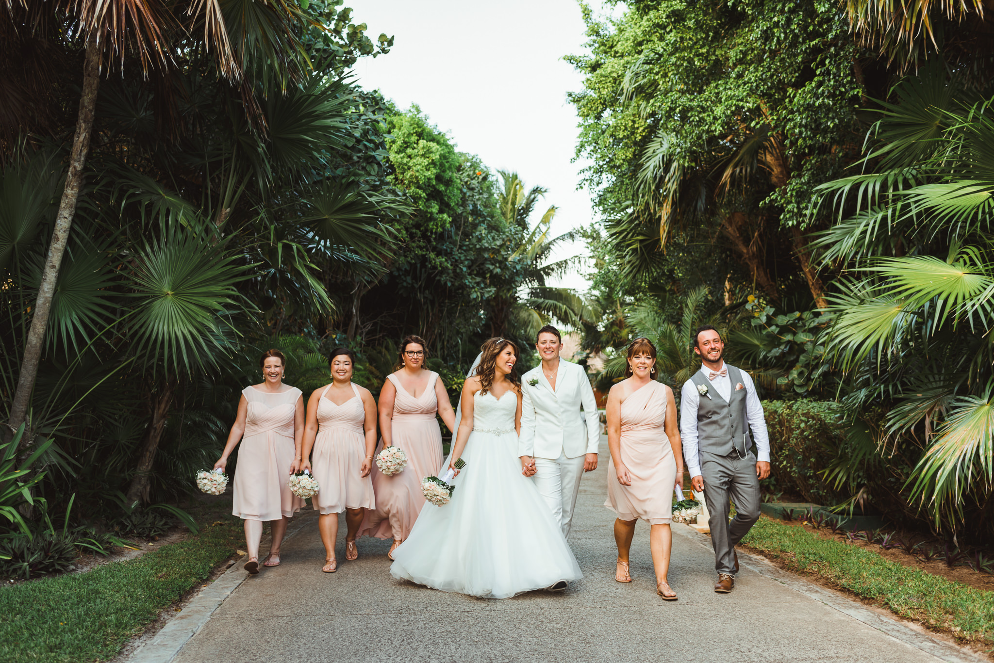 brides strolling through lush green tropical forest with wedding party Now Sapphire Resort beach ceremony Mexico