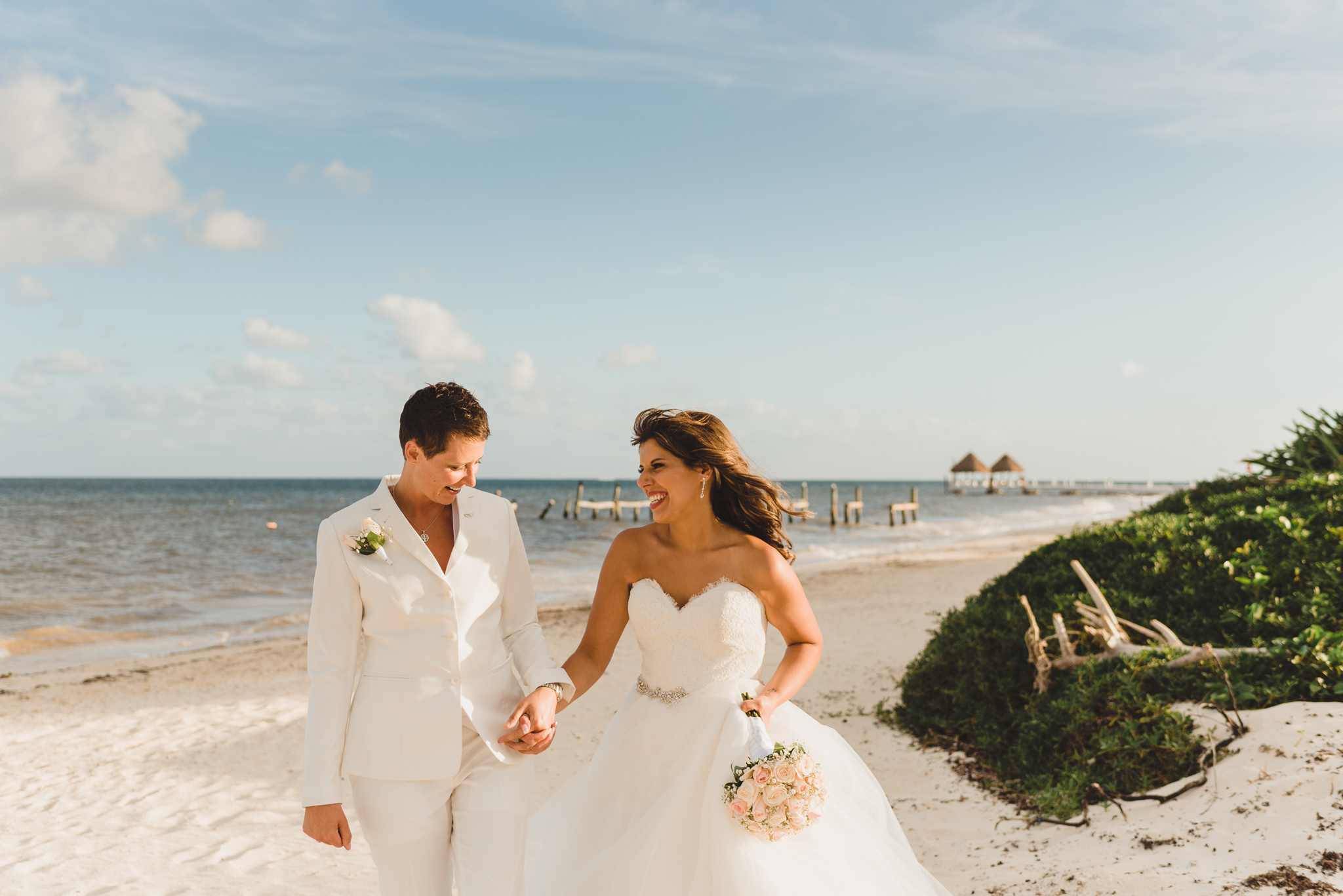 brides walking along beach holding hands after ceremony at Now Sapphire Resort in Mexico