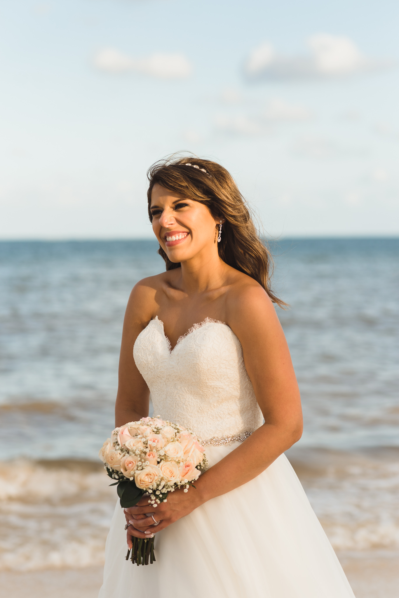 bride smiling and holding bouquet on the beach after ceremony at Now Sapphire Resort in Mexico