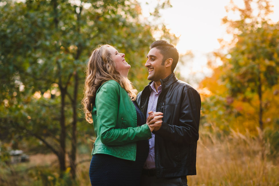 pregnant couple laughing while they slow dance in High Park, Toronto during autumn