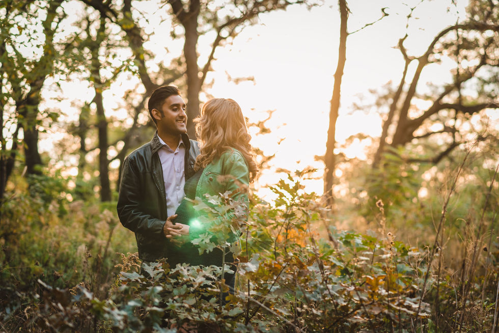 pregnant couple standing amongst the autumn foliage of High Park, Toronto