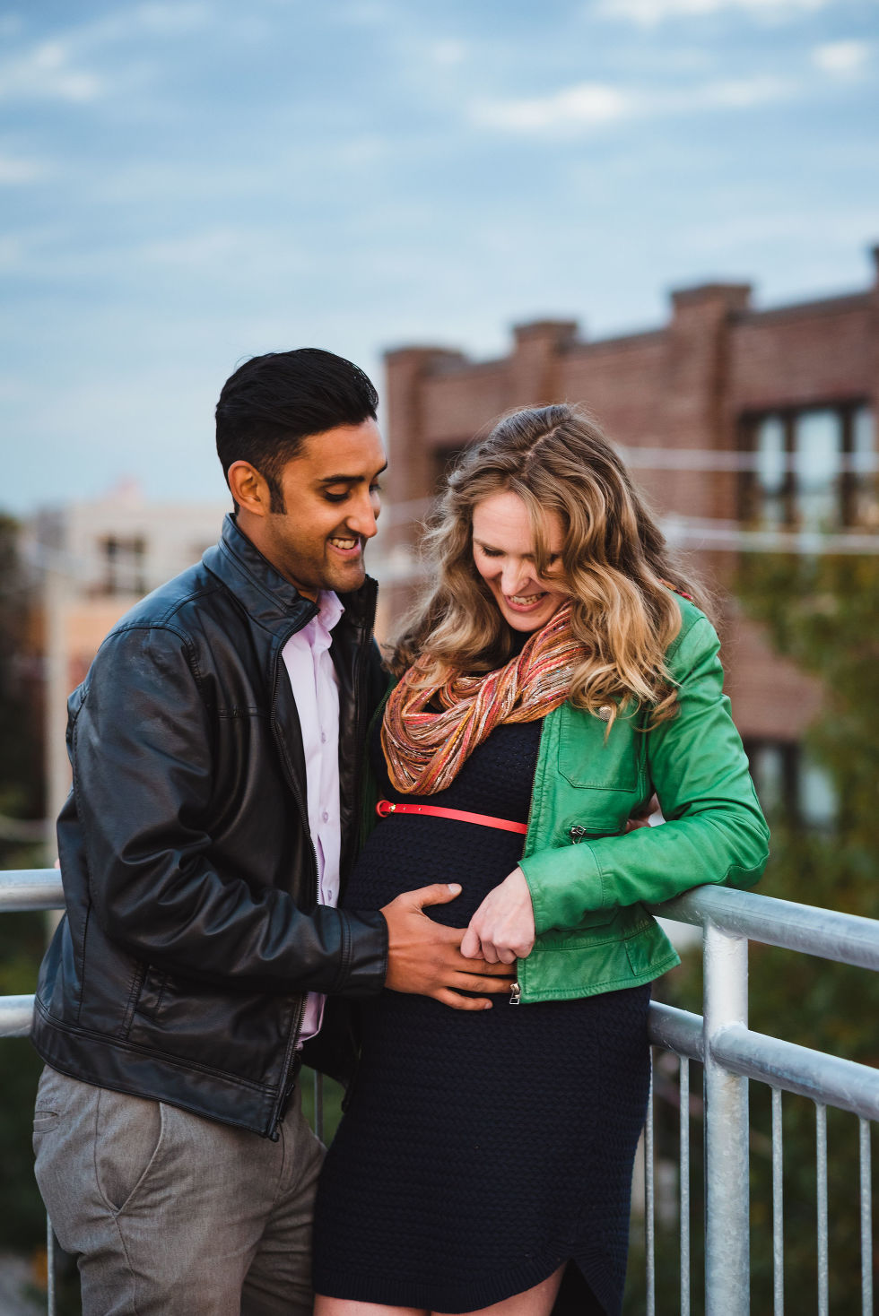 man and woman smiling as they hold her pregnant belly