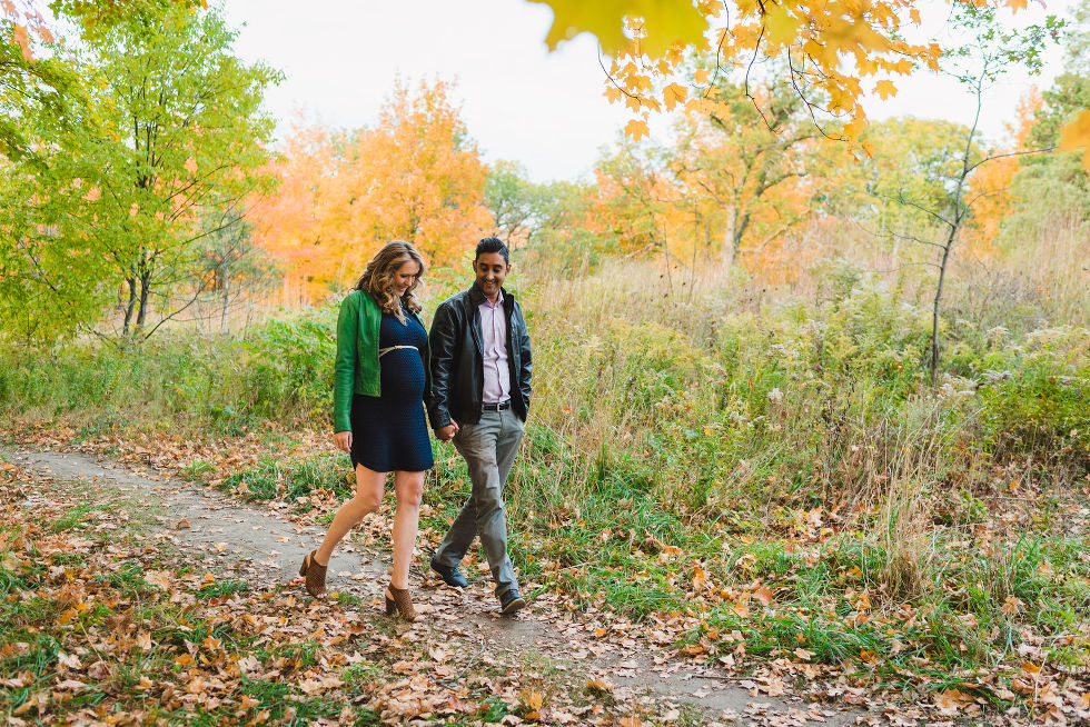 Pregnant couple walking along path with autumn foliage in High Park, Toronto