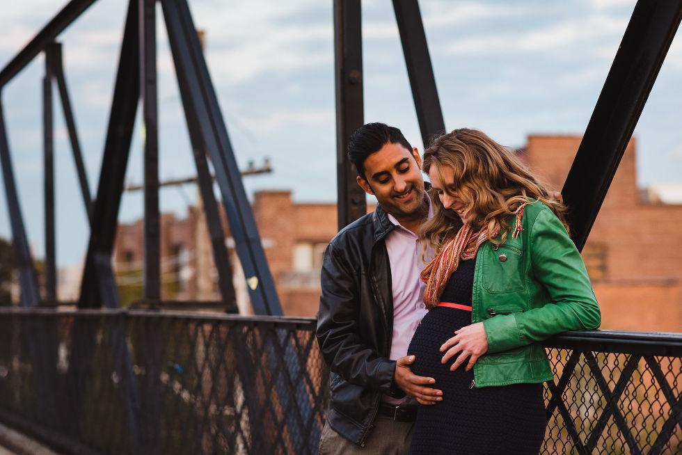man smiles as he touches his partners pregnant belly on a bride in the Junction, Toronto