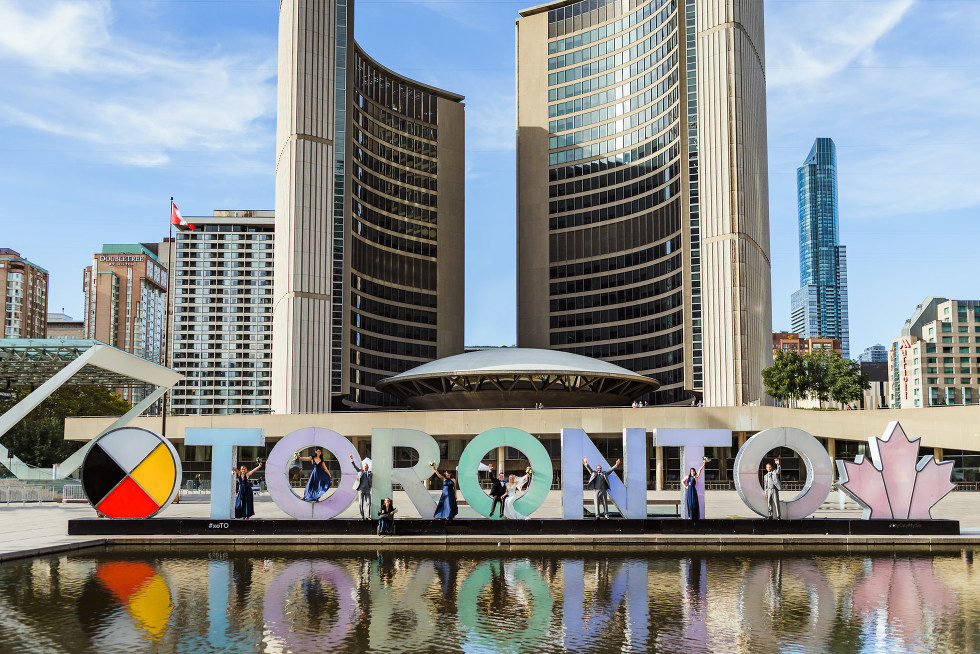 married couple and their wedding party standing in the letters of the Toronto sign at Nathan Phillips Square how to plan an amazing iconic downtown Toronto wedding