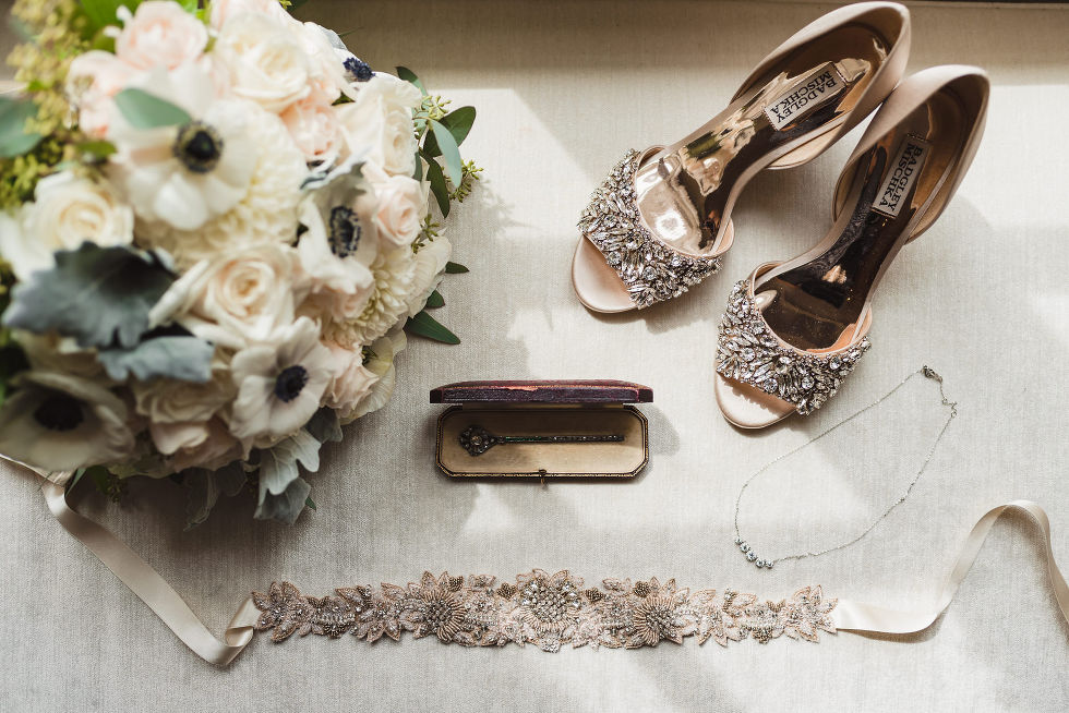 Brides shoes, jewellery, and floral bouquet laying on table before wedding at La Paletta Mansion in Burlington Ontario