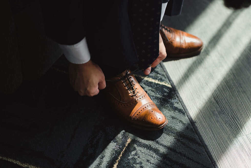 light pouring in on a grooms brown dress shoes as he prepares for his wedding at Fantasy Farms in Toronto Ontario