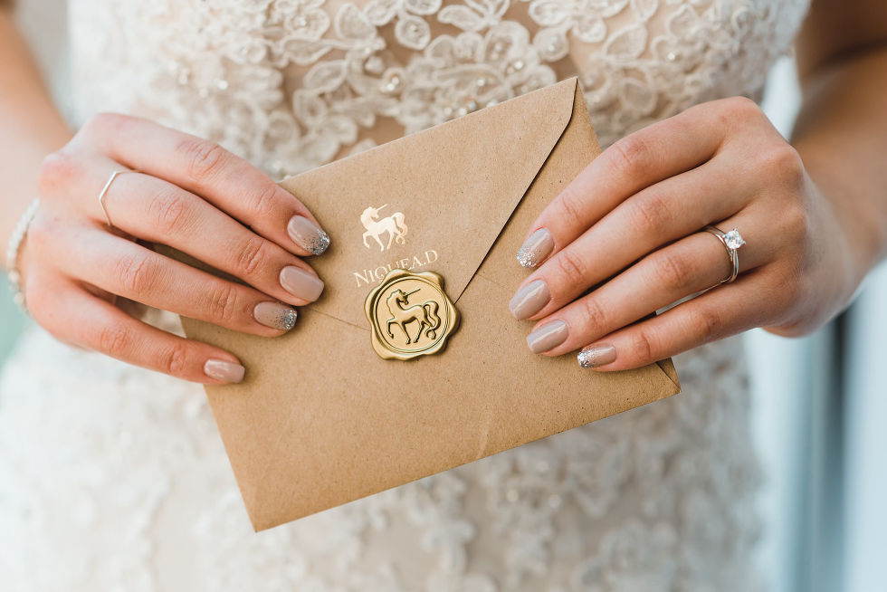 bride with painted nails holding wedding invitation with unicorn stamp on envelope Fantasy Farms in Toronto Ontario