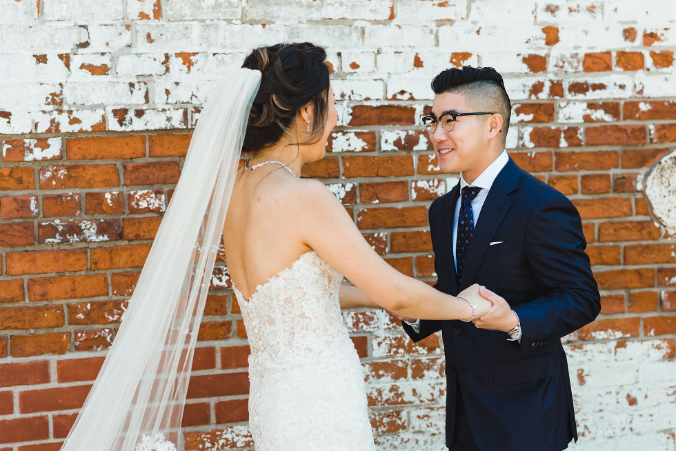 bride and groom wearing black framed glasses holding hands during first look before ceremony atFantasy Farms in Toronto Ontario