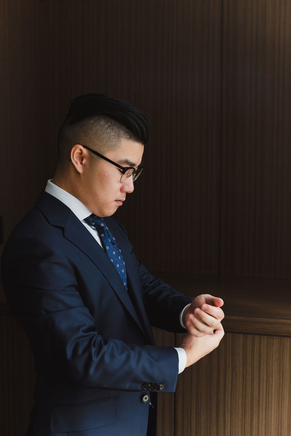 groom attaching his cufflinks to his blue suit before his wedding at Fantasy Farms in Toronto Ontario