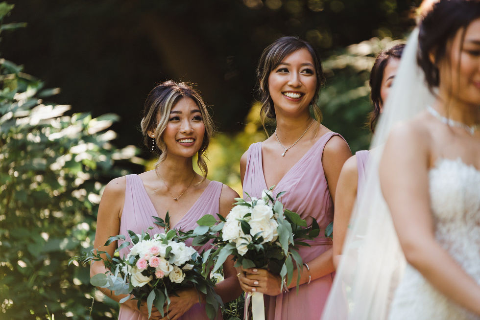 bridesmaids wearing lavender holding pink and white flower bouquets smiling at bride at Fantasy Farms in Toronto Ontario