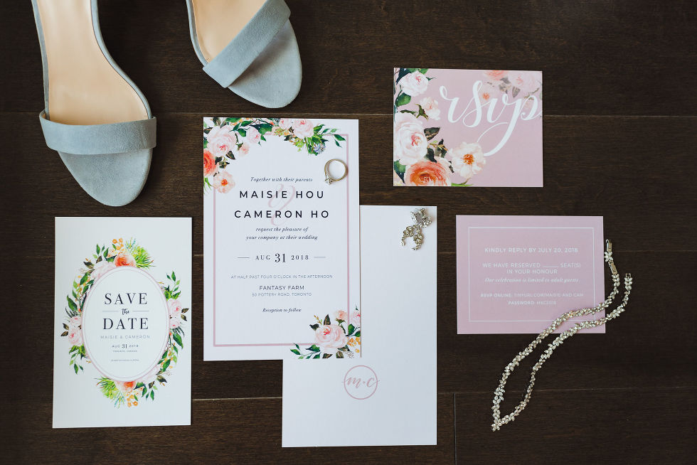 Save the date card, RSVP card, jewellery, and brides shoes on a dark wooden table at Fantasy Farms in Toronto Ontario 