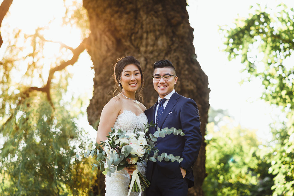 groom and bride holding white and green floral bouquet in front of golden hour sunlight at Fantasy Farms in Toronto Ontario