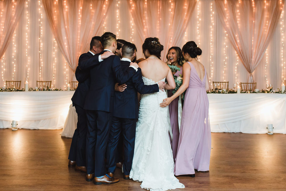 bridal party in a circle in front of white curtains at wedding venue at Fantasy Farms in Toronto Ontario