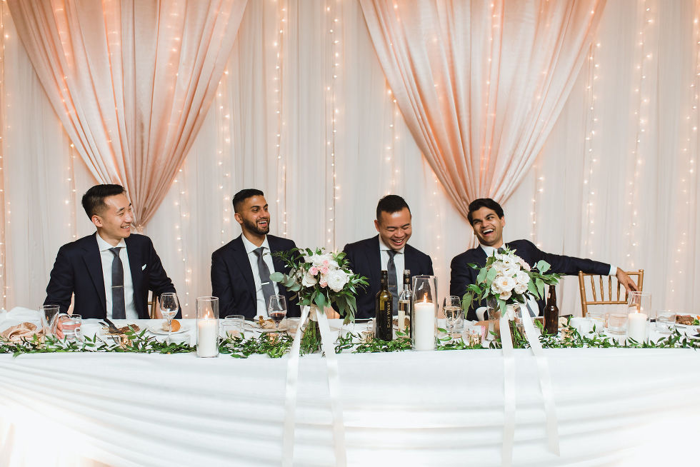 groomsmen laughing with twinkle lights and white sheer curtains at Fantasy Farms in Toronto Ontario
