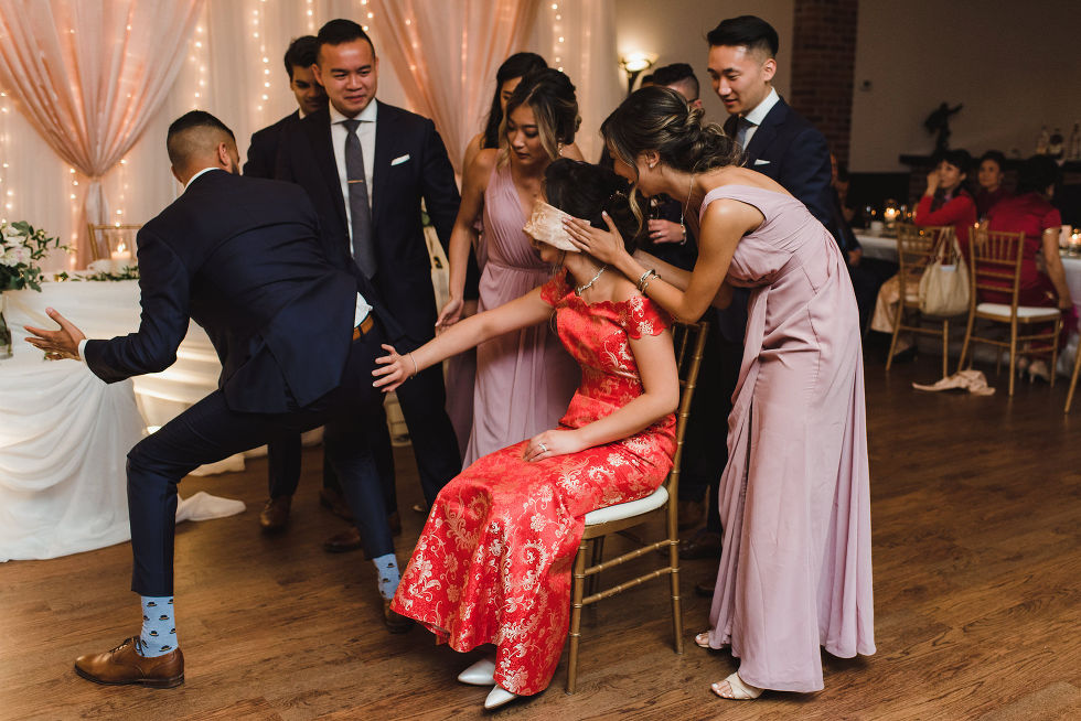 bride wearing a red dress and groom playing wedding games at reception with their bridal party at Fantasy Farms in Toronto Ontario
