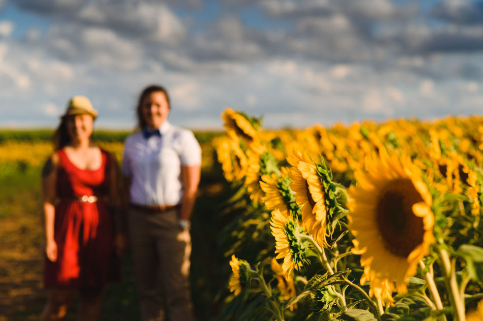 2 women standing next to a stunning sunflower field for their engagement photoshoot
