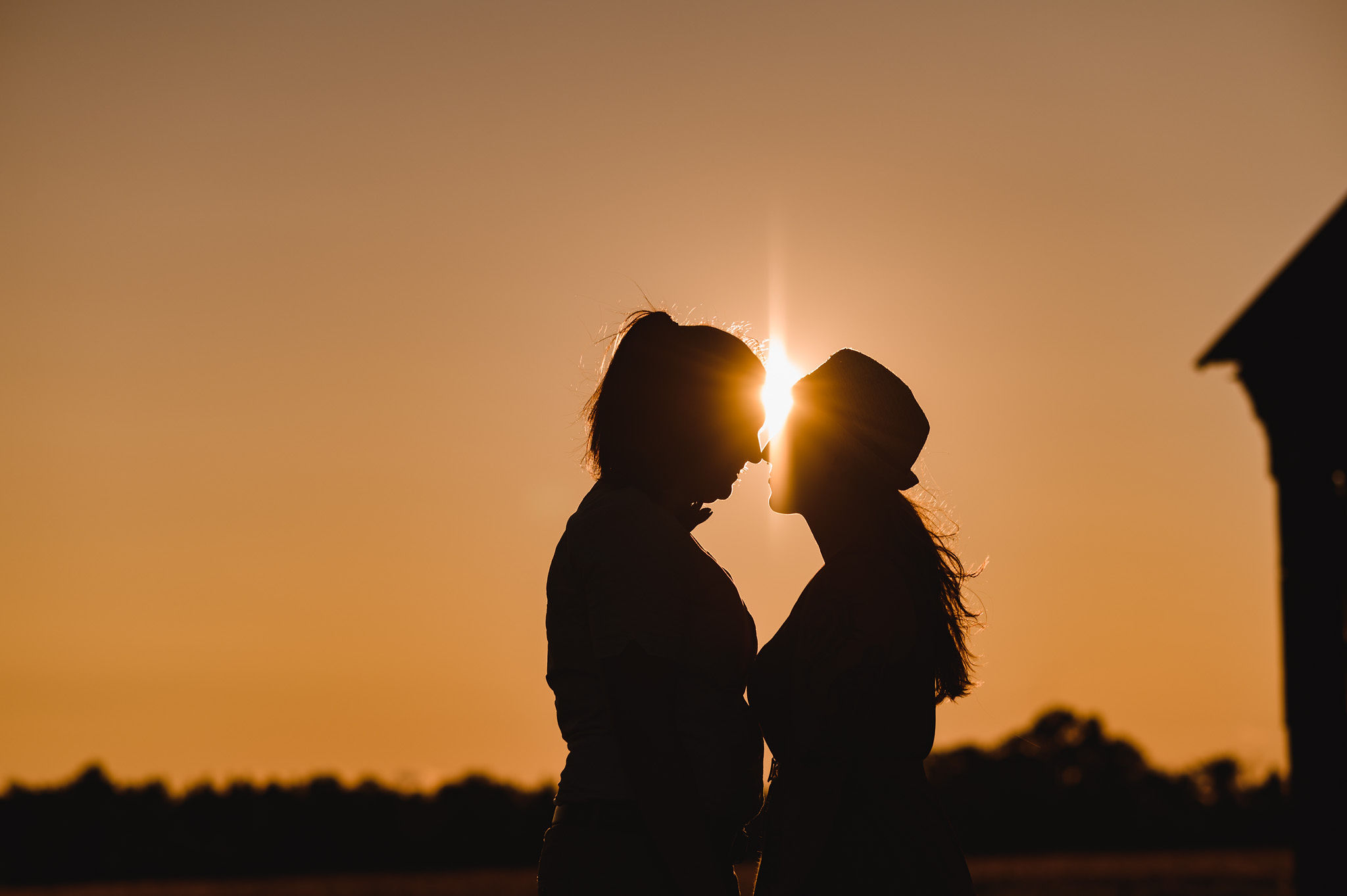 engaged couple in a loving embrace with the sun setting behind them stunning sunflower engagement photos