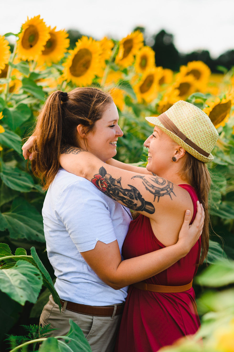 2 women with their arms wrapped around each other while standing in stunning sunflower field Toronto engagement photos