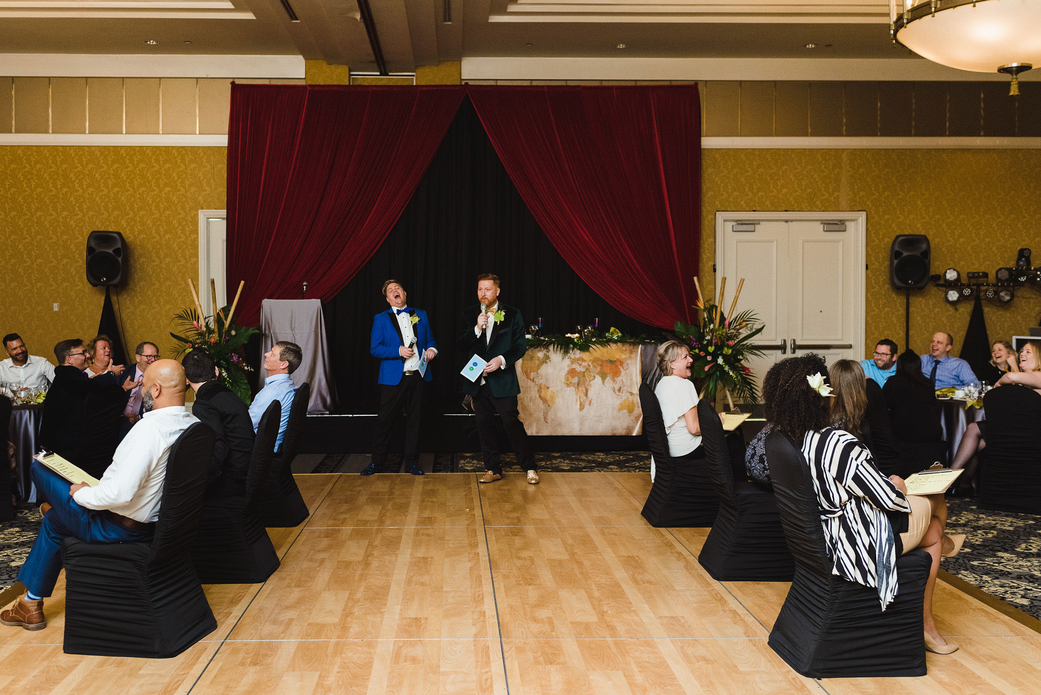 grooms laughing and reading out questions to their guests for their game during their fun wedding at the Hilton Fallsview in Niagara Falls
