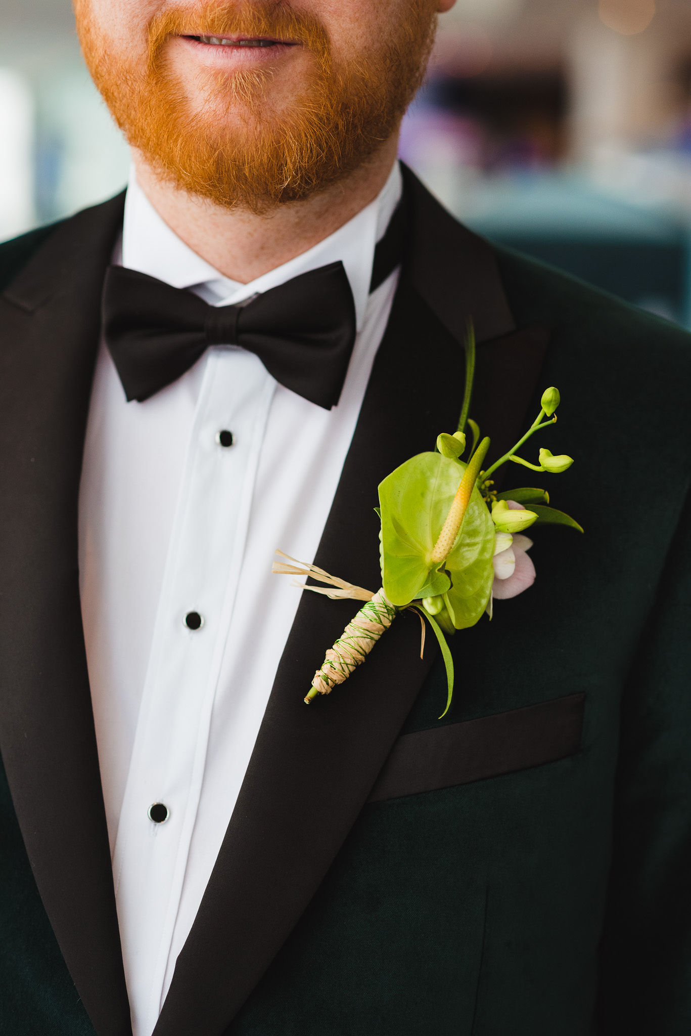 groom in a green suit and dark bowtie with a green boutonniere on his lapel before his wedding at the Hilton hotel in Niagara Falls 