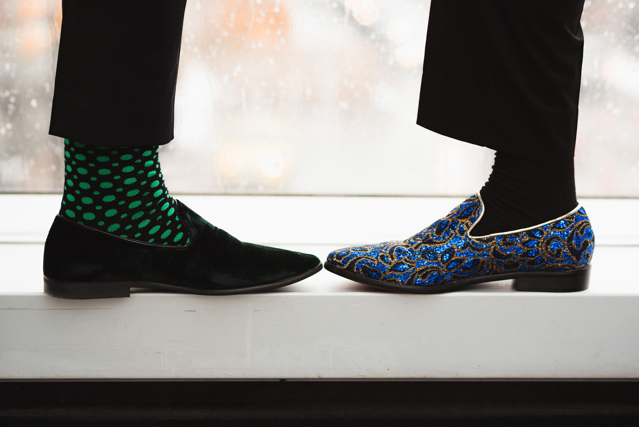 groom with black shoes and bright green socks and another groom with black socks and bright blue shoes before their wedding at the Hilton Fallsview in Niagara Falls