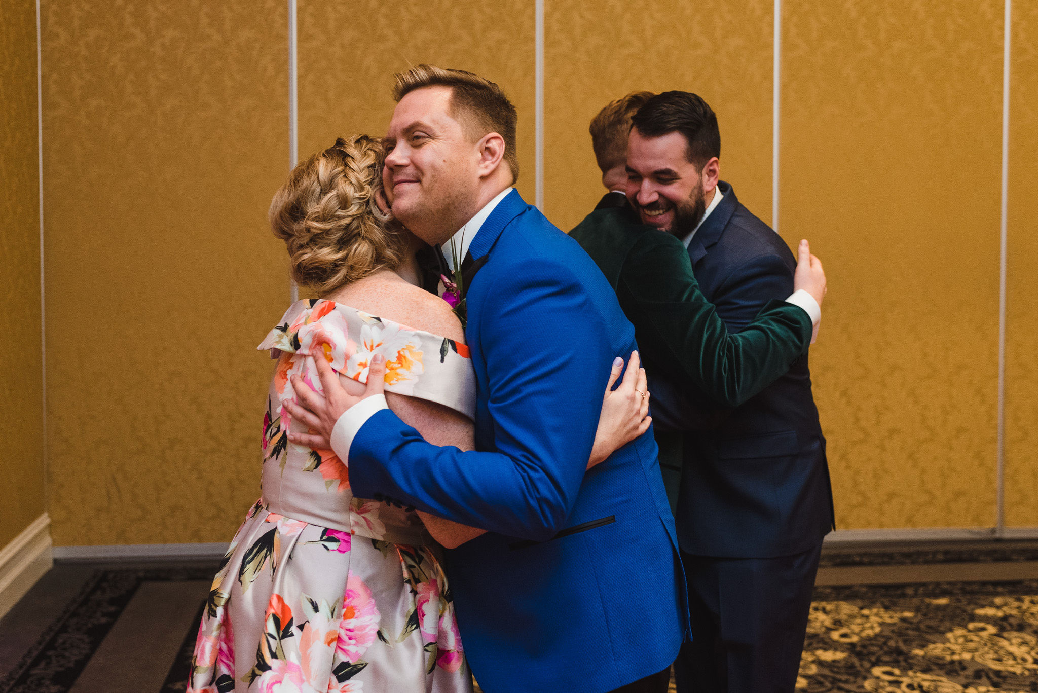 grooms hugging their guests as they arrive in the golden banquet room at the Hilton Fallsview in Niagara Falls