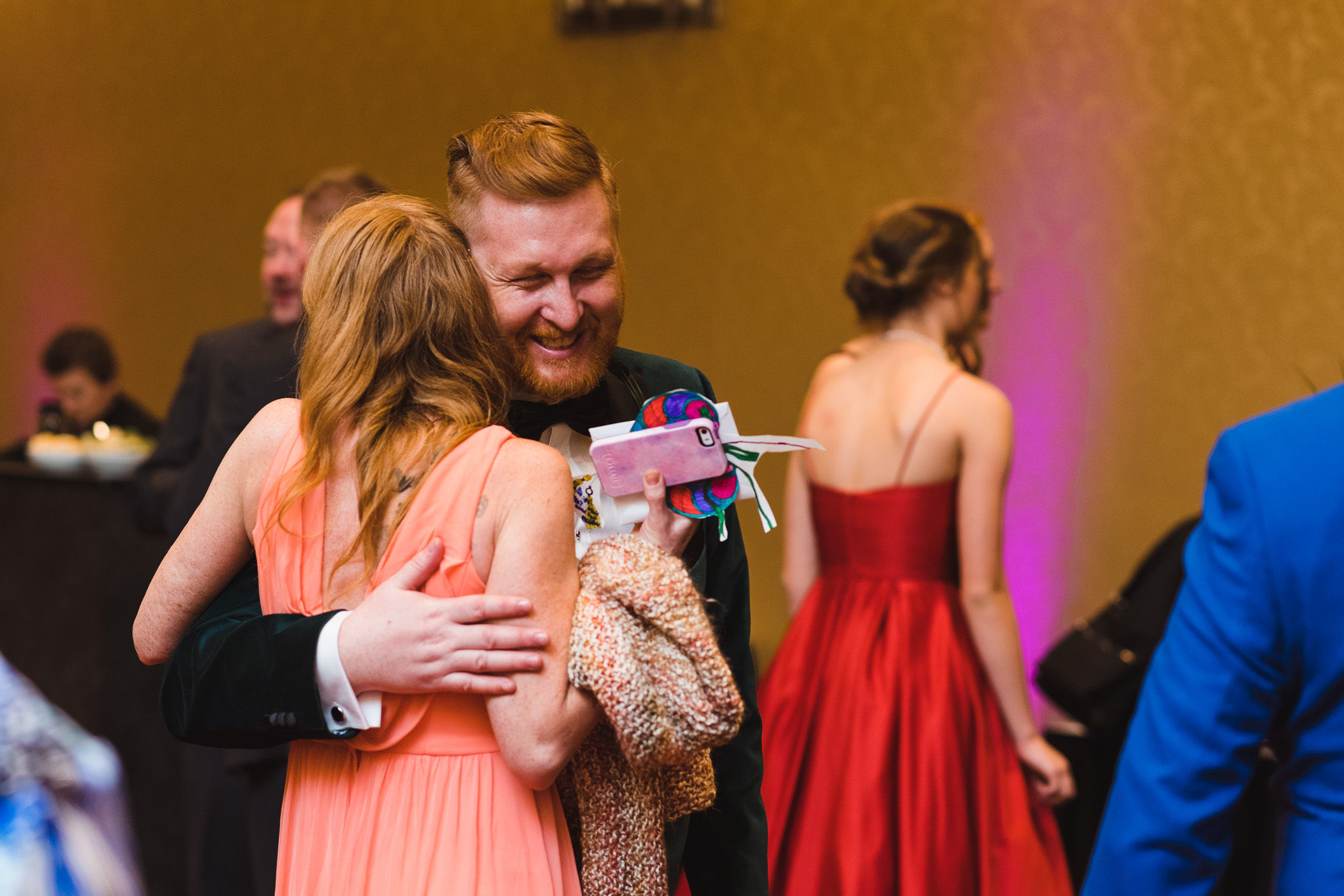 groom smiling as he hugs a wedding guest in a peach dress during his wedding at the Hilton Fallsview in Niagara Falls